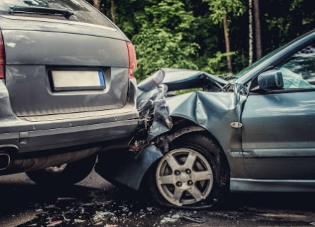 Two cars involved in a collision with visible damage on a road.